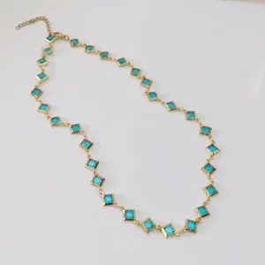 Macro view of a golden stainless steel necklace featuring elegant blue rhombus crystals