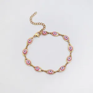 Dettaglio ravvicinato delle perline rosa evil eye su un bracciale in acciaio dorato