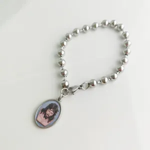 Detail of a silver stainless steel bead bracelet with a religious Jesus Christ oval pendant