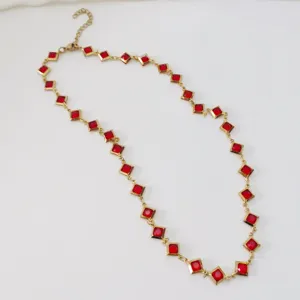 Detailed view of a gold-tone stainless steel necklace with vibrant red square gems.