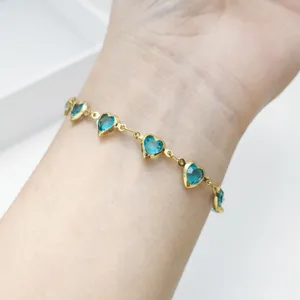 Detailansicht eines goldfarbenen Edelstahlarmbands mit herzförmigen blauen Glassteinen