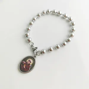 Detail shot of a stainless steel ball bead bracelet with a religious saint pendant.