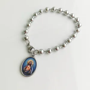 Close-up detail of silver stainless steel ball chain bracelet with Jesus oval pendant