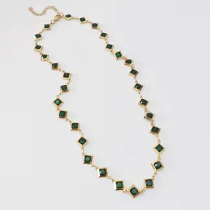 Close-up of elegant stainless steel necklace with green diamond-shaped stones