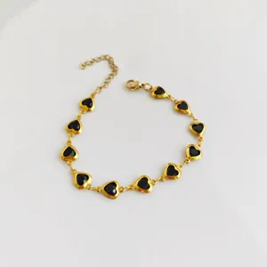 Close-up view of a gold stainless steel heart bracelet with black enamel centers