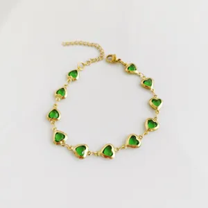Detailed view of gold stainless steel bracelet with vivid green heart-shaped stones.
