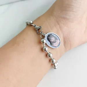 Close-up of stainless steel ball chain bracelet with Jesus Christ oval pendant on wrist