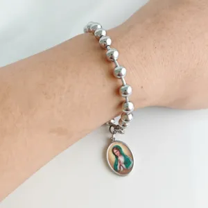 Stainless steel beaded bracelet with religious Virgin Mary pendant shown on a wrist