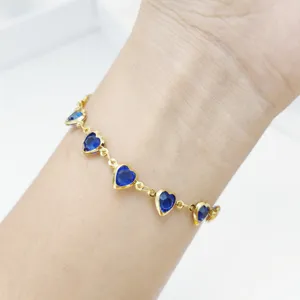 Detailaufnahme eines vergoldeten Edelstahlarmbands mit blauen herzförmigen Glassteinen.