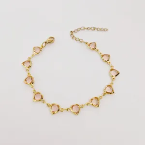 Nahaufnahme eines goldenen Edelstahlarmbands mit facettierten rosa Herzglassteinen