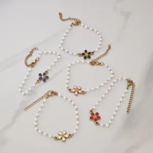 Detail shot showing colorful enamel daisy charms on delicate imitation pearl gold bracelets