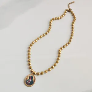 Detailopname van een gouden roestvrijstalen rozenkrans ketting met Maagd Maria hanger