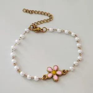 Close-up of stainless steel pearl bracelet with pink daisy flower charm detail