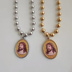 Macrodetail van goud- en zilverkleurige roestvrijstalen rozenkranskettingen met Jezus-hangers.