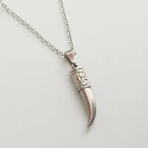 Macro view of a stainless steel fang pendant with intricate retro engraved details