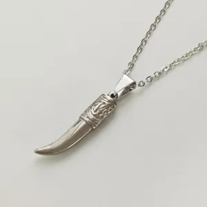 Detailed view of vintage silver stainless steel fang pendant with intricate engravings