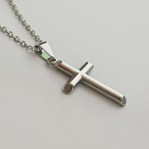 Close-up of minimalist stainless steel cross pendant necklace on white background