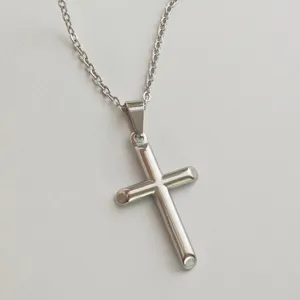 Close-up of minimalist stainless steel cross pendant on a silver-toned metal chain