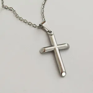 Detailed view of a polished stainless steel cross pendant on a matching chain necklace