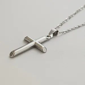 Close-up of minimalist stainless steel cross pendant and cable chain detail