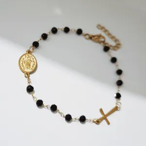 Detailansicht eines 18K vergoldeten Edelstahl-Perlenarmbands mit Kreuz und Medaille.