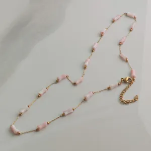 Detail of stainless steel necklace featuring pink bamboo-shaped beads and gold chain
