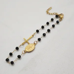 Detailansicht eines vergoldeten Rosenkranz-Armbandes mit schwarzen Perlen und Medaille.