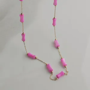 Detailed close-up showing vibrant pink bamboo-style beads on a gold stainless steel necklace