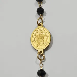 Detailaufnahme der vergoldeten San Judas Tadeo Medaille an schwarzer Perlenkette
