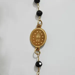 Detailaufnahme der 18K vergoldeten Wundertätigen Medaille an einem schwarzen Perlenarmband.