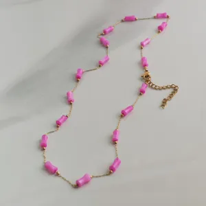 Close-up of pink bamboo-shaped beads on a dainty gold stainless steel chain necklace