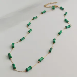 Detail of stainless steel gold chain necklace featuring green bamboo-shaped beads
