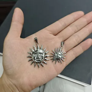 Vista detallada de dos colgantes de sol de acero inoxidable que muestran tamaños en una mano.