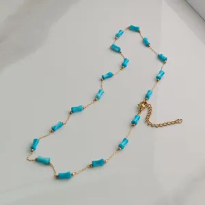 Close-up detail of a gold stainless steel necklace featuring vibrant blue bamboo-shaped beads