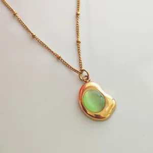 Detailed macro view of a vintage 18K gold plated necklace featuring a green cat eye pendant.