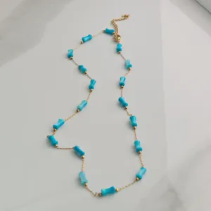 Detail shot of a stainless steel gold necklace with vibrant blue bamboo-shaped beads.