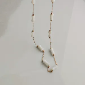 Close-up detail of a minimalist stainless steel chain with white bamboo-style segments