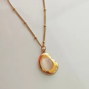Close-up detail of a vintage 18K gold-plated bean pendant with translucent stone inlay.