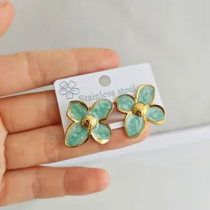 Close-up of green enamel four-petal flower earrings crafted from gold-tone stainless steel