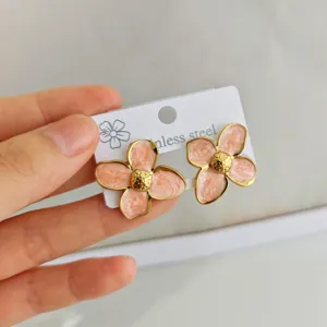 Detailed macro view of pink marble enamel four-petal flower earrings in stainless steel