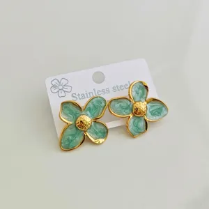 Detail of green enamel four-petal flower earrings with stainless steel gold plating.