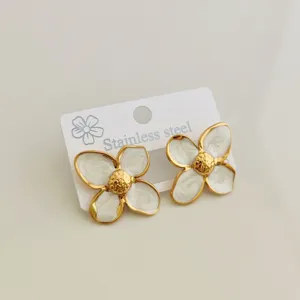 Detailed view of vintage stainless steel flower stud earrings with white enamel glaze