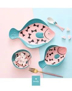 Assiettes et bols en céramique peints à la main en forme de poisson sur fond rose et bleu