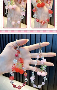 Detailed macro view of beaded cherry phone strap featuring pink and red crystal beads