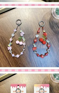 Close-up view of two handmade cherry beaded charms for mobile phones or bags on table