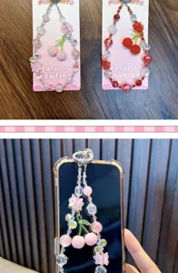 Handmade cherry beaded phone charm strap shown on display card and a phone case
