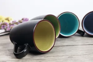 Detailed view of the matte black ceramic mugs with vibrant interior glaze colors