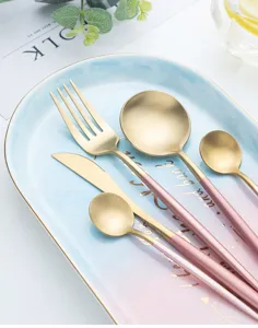 Primer plano de juego de cubiertos de acero inoxidable dorado y rosa en un plato