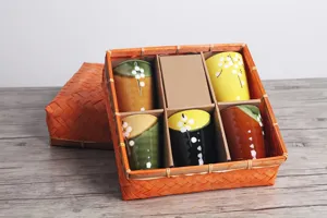Vista detallada de un juego de cinco tazas de té de cerámica japonesa en caja de bambú.