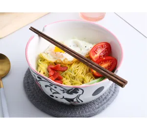 Detail of cartoon cat ceramic ramen bowl with chopsticks and fresh noodles
